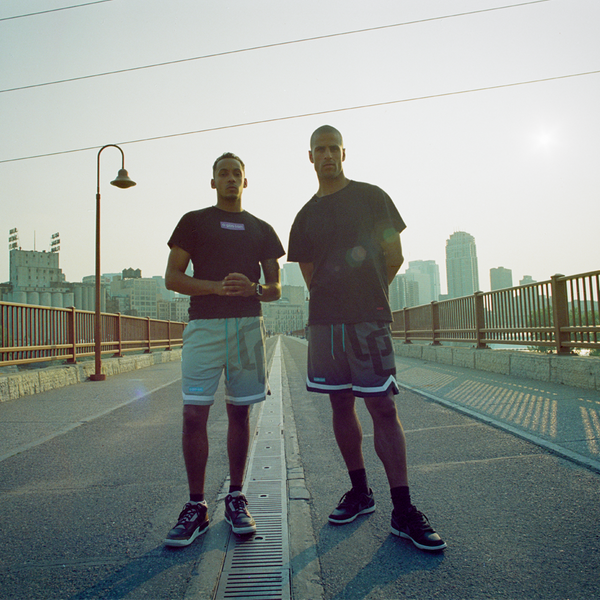 Two men standing on a bridge with a city skyline in the background