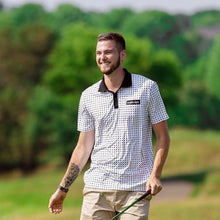 Load image into Gallery viewer, Man walking on a golf course wearing a patterned polo shirt with a brand logo.