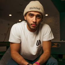 Load image into Gallery viewer, Man wearing a white t-shirt and beanie sitting on a bench.